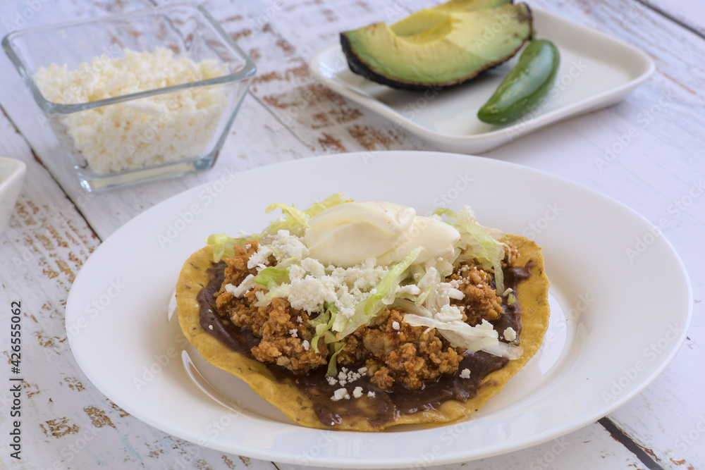 Traditional Mexican food. Picadillo toast with sour cream, lettuce and cheese, accompanied by avocado slices.