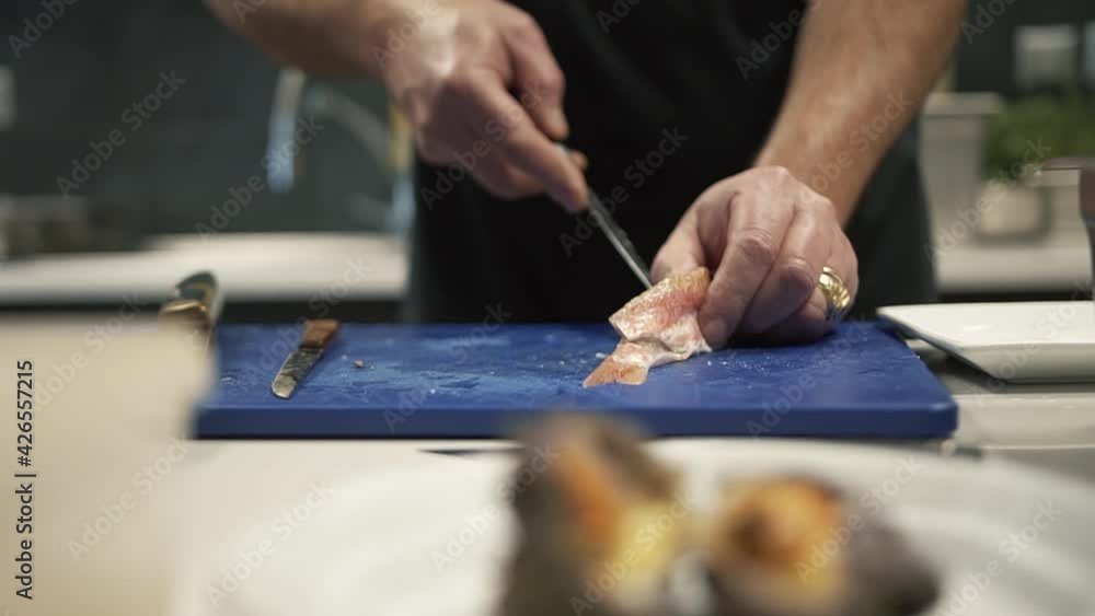 Chef cutting raw Scorpaena fish or rockfish into pieces Chef cutting raw Scorpaena fish or rockfish into pieces