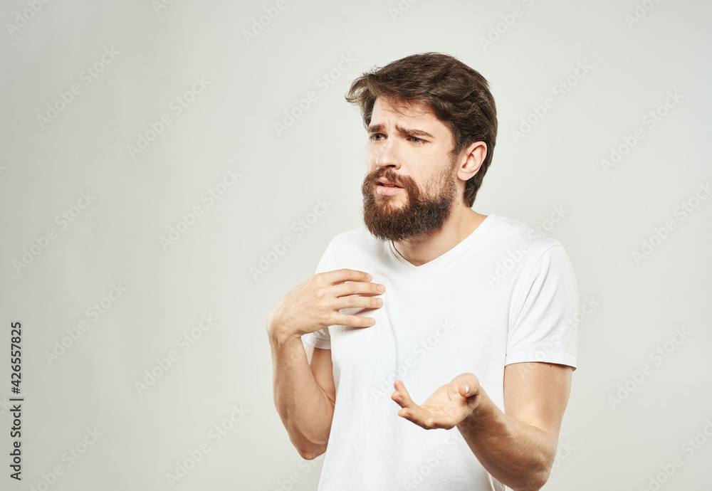 A man in a white t-shirt on a light background emotions model gesturing with hands Copy Space A man in a white t-shirt on a light background emotions model gesturing with hands Copy Space