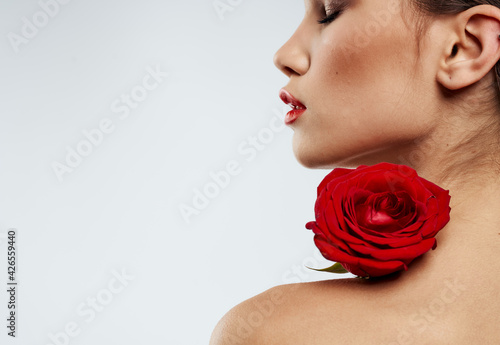 Romantic woman with red fragrant flower near the face clean skin cosmetology dermatology