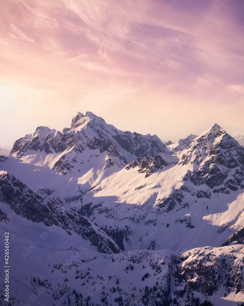 Aerial View from Airplane of Blue Snow Covered Canadian Mountain Landscape in Winter. Colorful Pink Sky Art Render. Tantalus Range near Squamish, North of Vancouver, British Columbia, Canada.