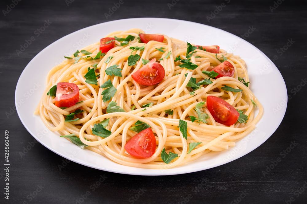 Pasta spaghetti with cherry tomatoes and parsley on a dark background Pasta spaghetti with cherry tomatoes and parsley on a dark background