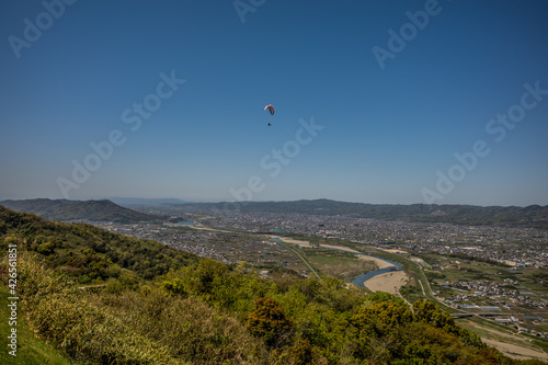 快晴の空の下を飛ぶパラグライダー。和歌山県紀の川市、寺山スカイスポーツから撮影