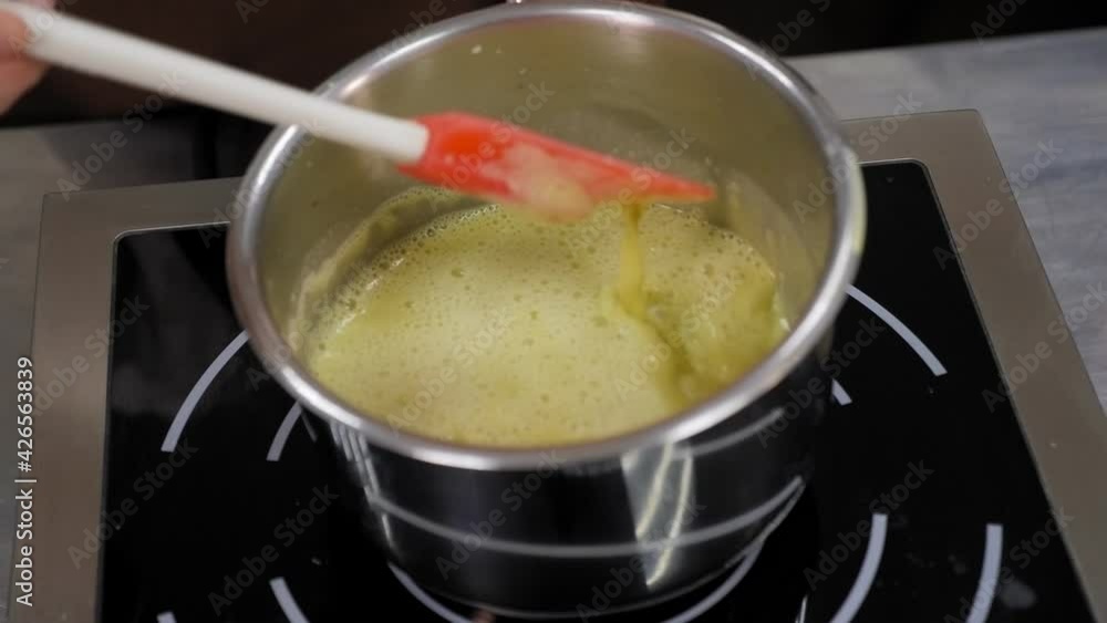 Close-up of a pastry chef preparing pistachio mousse in a saucepan. Close-up of a pastry chef preparing pistachio mousse in a saucepan.