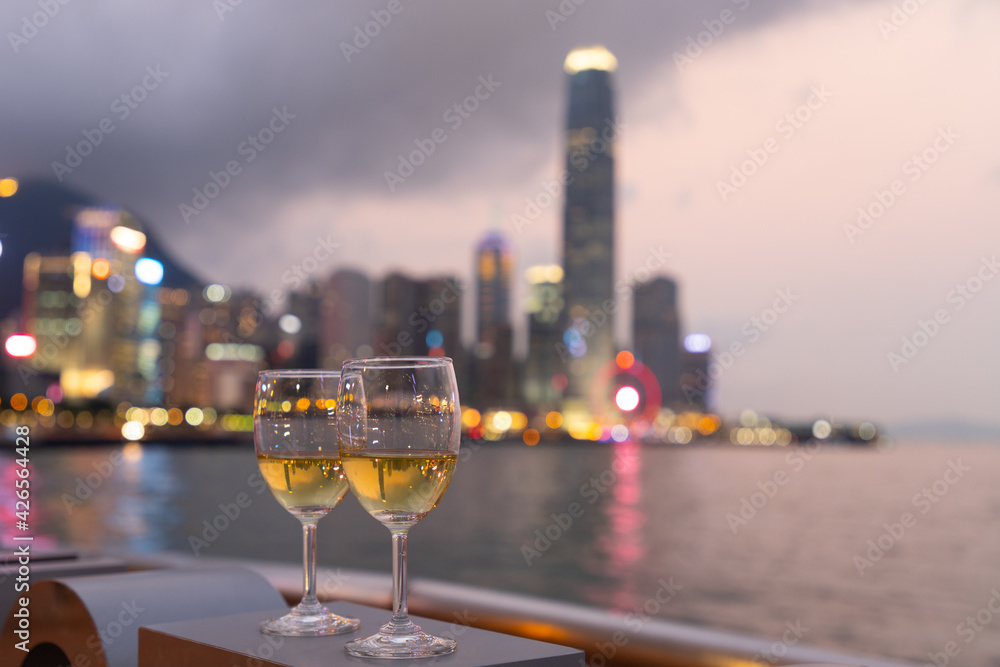two glasses wine with twinkling blurred city night lights in Central, Hong Kong Victoria Harbour as background, romantic concept for lovers and valentine