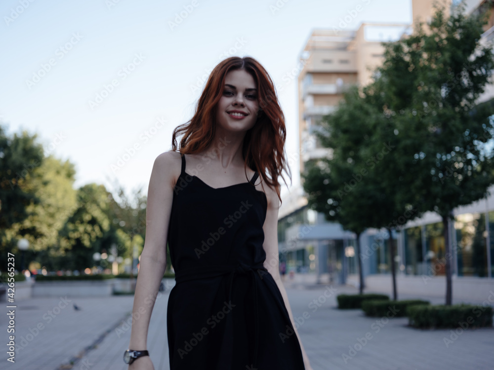 Fashionable Woman in a black dress walks down the street in the park in nature