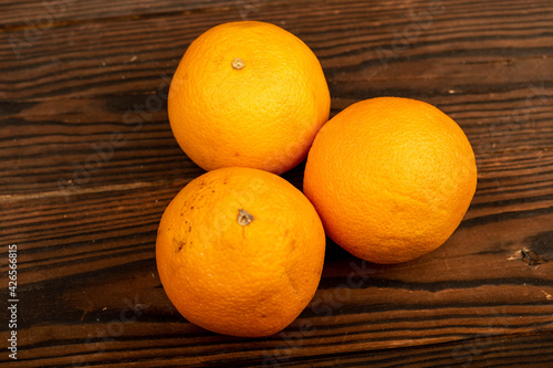 Three fresh juicy oranges on a wooden table.