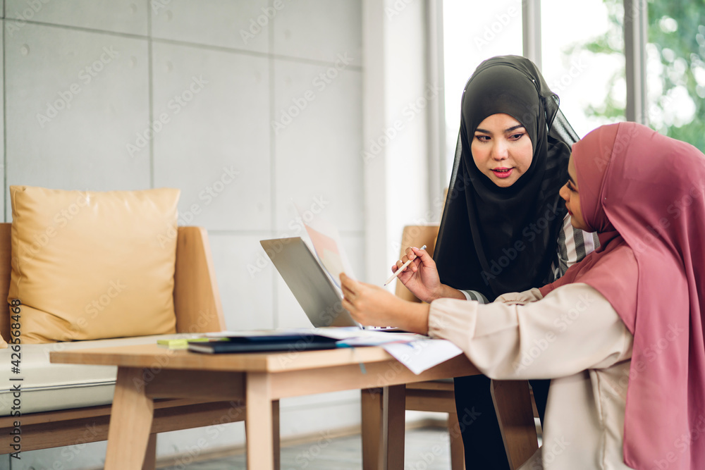 Young two smiling happy beautiful asian muslim woman relaxing using laptop computer working and video conference meeting at home.work from home concept Young two smiling happy beautiful asian muslim woman relaxing using laptop computer working and video conference meeting at home.work from home concept