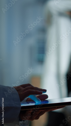 Close up of expert scientist in neurological dysfunctions standing in laboratory working at tablet. Medical researcher preparing patient for brain scan analysing electrical activity of nervous system