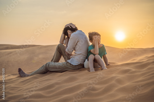 Relationship problems between father and son. Family conflict. Dad and son have a heated relationship, sit in the hot desert with their backs to each other and do not want to talk © galitskaya