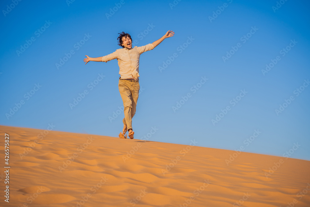Man traveling in the desert. Sandy dunes and blue sky on sunny summer day. Travel, adventure, freedom concept. Tourism reopens after quarantine COVID 19