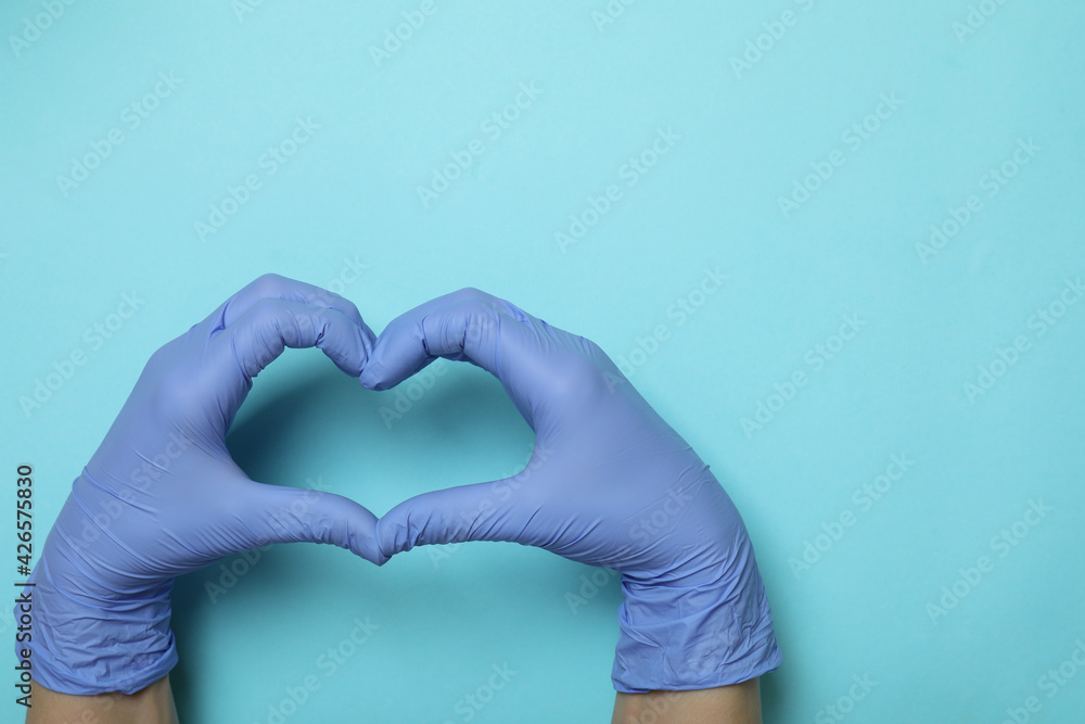 Obraz premium Hands in medical gloves shows heart on blue background