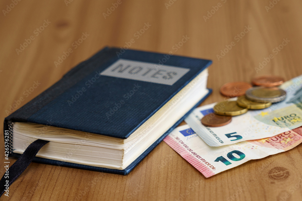 Notebook on the table next to euro banknotes and coins.