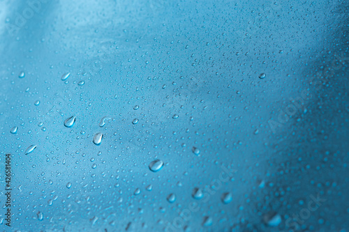Abstract blue background with raindrops and beautiful bokeh. The concept of autumn and the cold stormy weather. Texture of macro drops on the blurred background of the window. Loneliness sadness