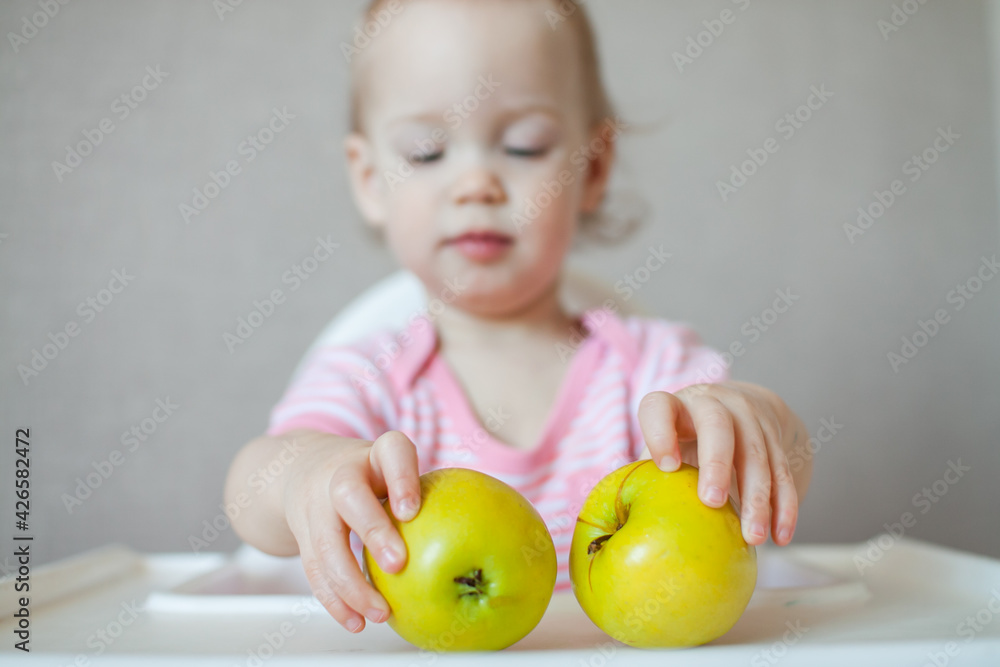 A little girl tastes, examines and plays with fresh apples with pleasure and interest. High quality photo A little girl tastes, examines and plays with fresh apples with pleasure and interest. High quality photo