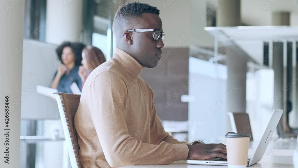 Video of concentrated black business man working with laptop in the office on coworking place.