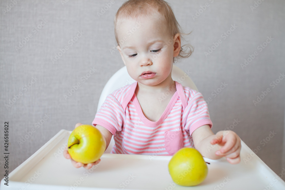 A little girl tastes, examines and plays with fresh apples with pleasure and interest. High quality photo A little girl tastes, examines and plays with fresh apples with pleasure and interest. High quality photo