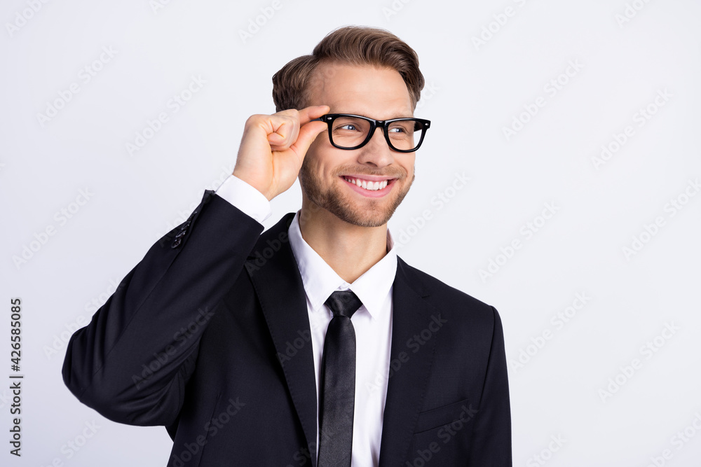 Photo of young handsome man happy positive smile hand touch glasses look empty space isolated over grey color background Photo of young handsome man happy positive smile hand touch glasses look empty space isolated over grey color background