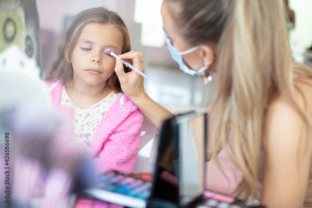 Mother helping her little girl with make up. Mother helping her little girl with make up.