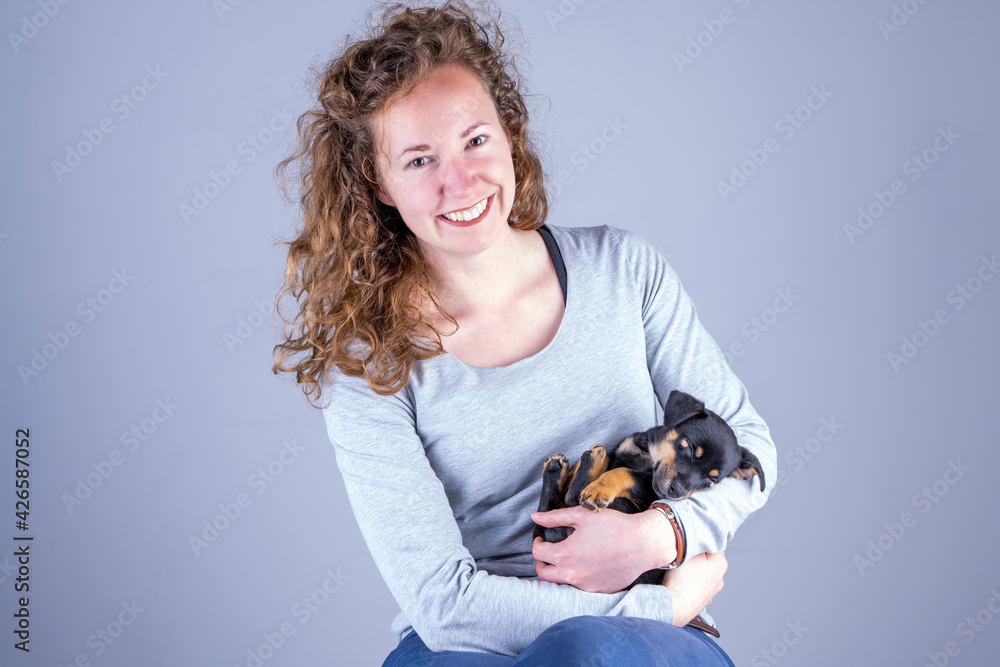 Part of a smiling female, she lovingly holds a tiny sleeping Jack Russel Terrier puppy in her arms Part of a smiling female, she lovingly holds a tiny sleeping Jack Russel Terrier puppy in her arms