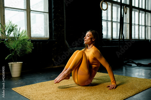 beautiful girl in a yellow sportswear is doing in yoga, breathing correctly. Modern sports hall