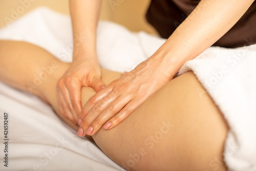 Closeup photo of the anticellulite massage by a physiotherapist. Young girl is relaxing in the spa. Foot massage. © Arina