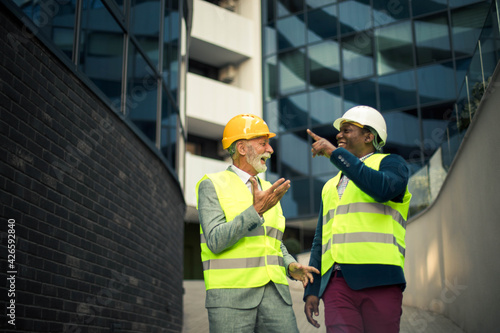 Mature engineer discussing the structure of the building with architects colleague at construction site. © liderina