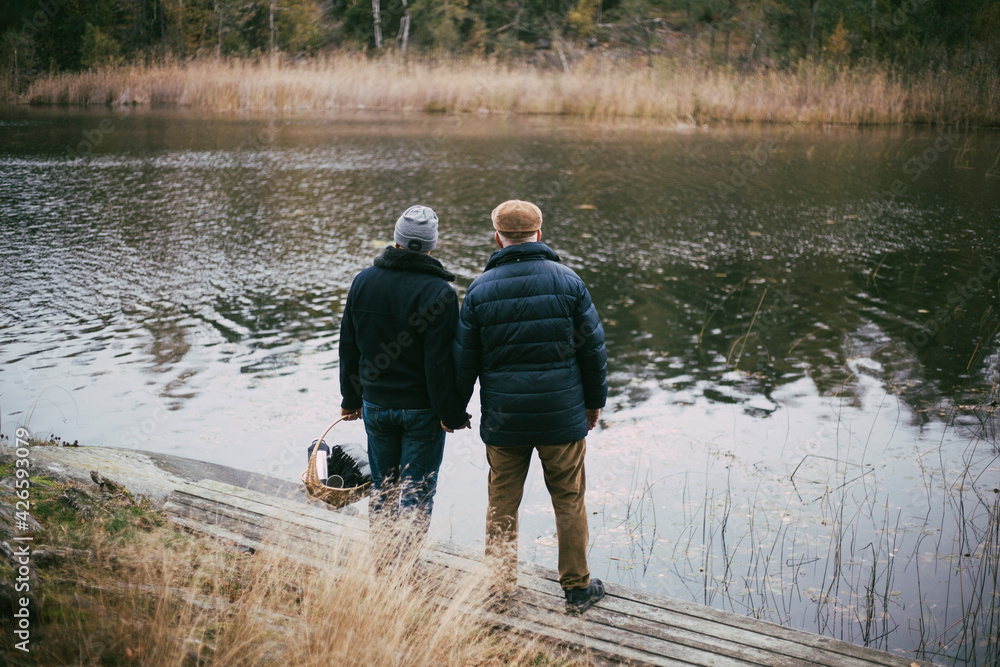 Rear view of gay couple admiring river while standing at riverbank Rear view of gay couple admiring river while standing at riverbank