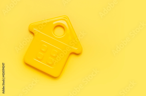 House symbol on yellow background flat lay top view copy space. Model of plastic yellow house. Concept of buying home, apartment. Renting a house, real estate. Mortgage, credit, real estate insurance