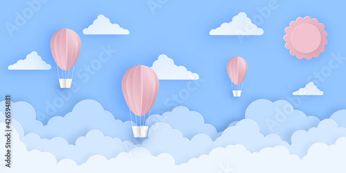 Pink beautiful hot air balloons flying over fluffy clouds in the sky with sun.