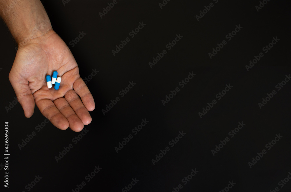 on the palm of an adult man are three tablets. On a black background. copy space on the palm of an adult man are three tablets. On a black background. copy space