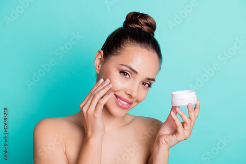 Portrait of attractive cheerful girl holding in hands applying cream collagen freshness isolated over bright teal turquoise color background