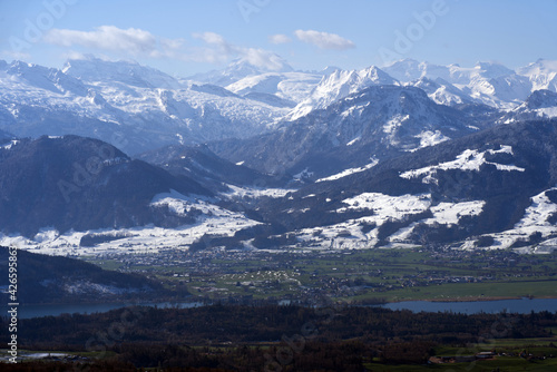 Panoramic landscape with lake Zurich and snow capped Swiss alps in the background. Photo taken April 8th, 2021, Zurich, Switzerland.