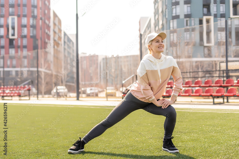 Fitness and sports. Young woman doing stretching at the stadium