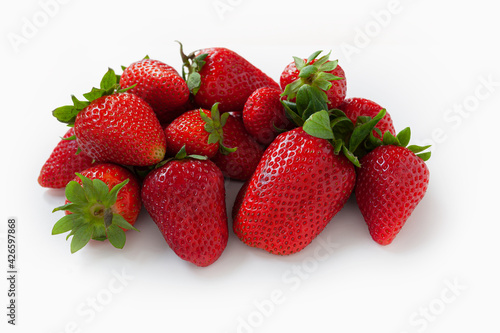 Group of fresh, ripe red strawberries with green leaves on white background
