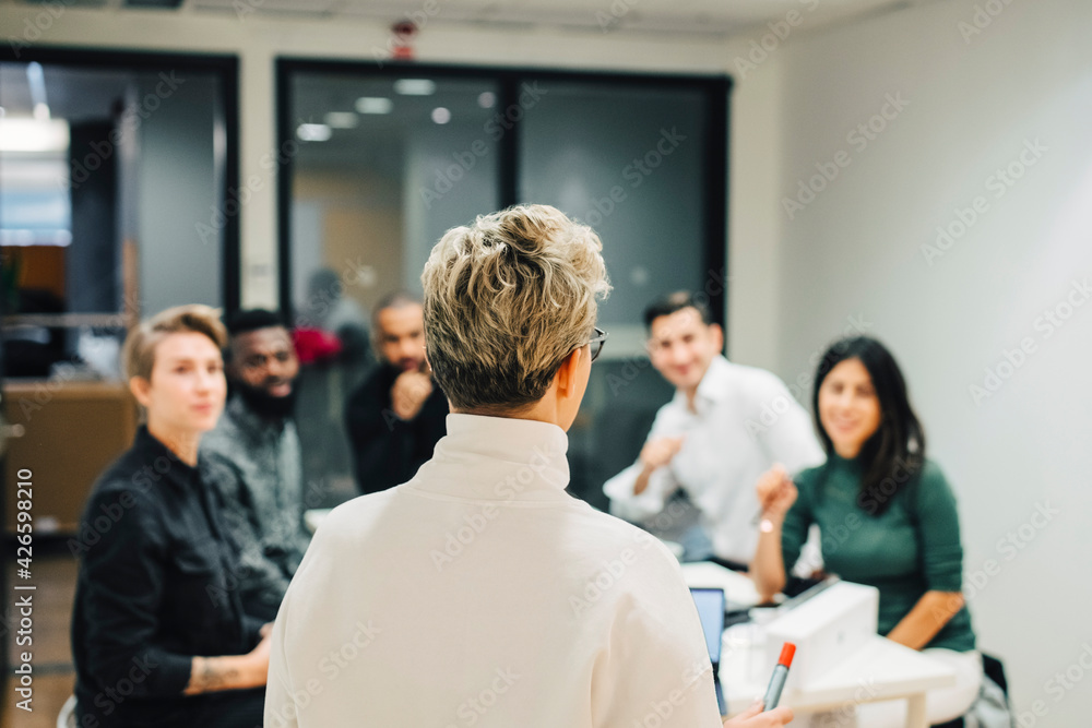 Businesswoman discussing with colleagues in board room at office Businesswoman discussing with colleagues in board room at office