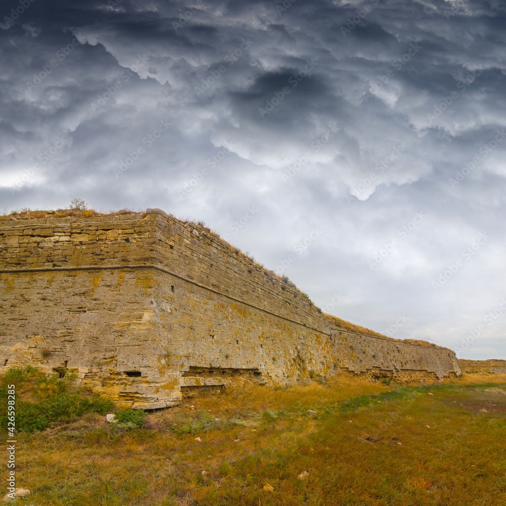 oldmedieval fortress among prairie under dense cloudy sky