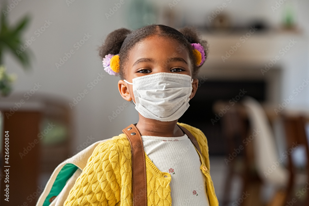 Cute little girl wearing face mask at home before going to school foto