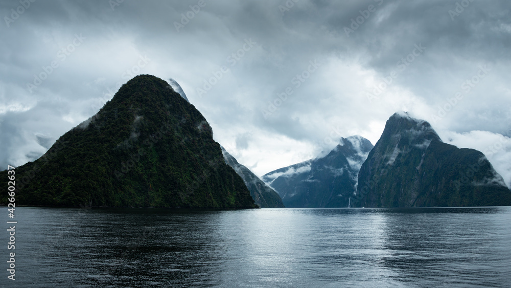 Clouds drifting over moody Mitre Peak and 151m-tall Stirling Falls, Milford Sound, New Zealand