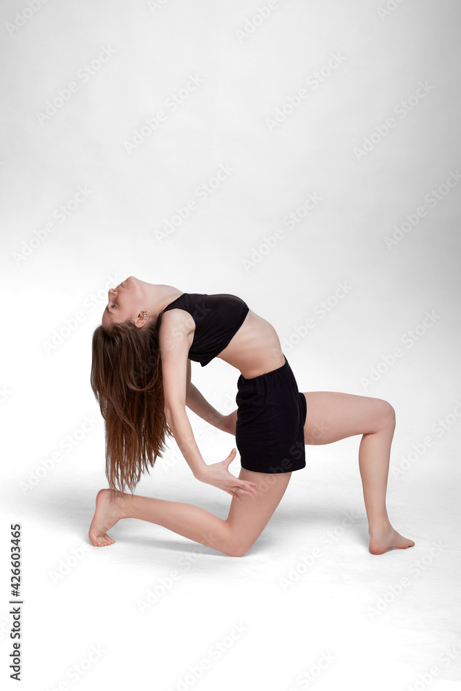 Young slim athletic girl, with long hair, in a black top and shorts, in the studio on a white background Young slim athletic girl, with long hair, in a black top and shorts, in the studio on a white background