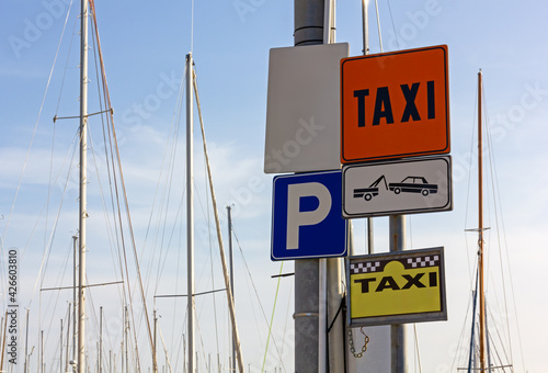 Group of colorful signs in a marina, with sailboat masts in the background