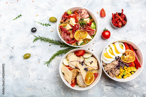 Set healthy light diet salad in paper bowl package for take away or food delivery. caesar, tuna, ham, prosciutto, chicken, delivery food in containers. place for text, top view