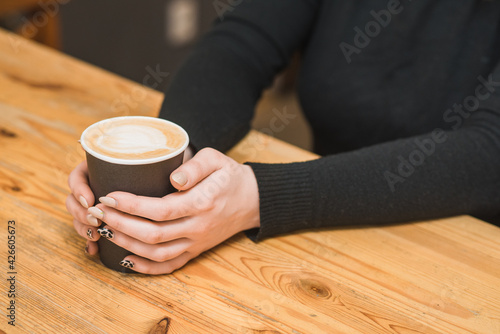Photo with female hands holding a glass of coffee in the cafeteria