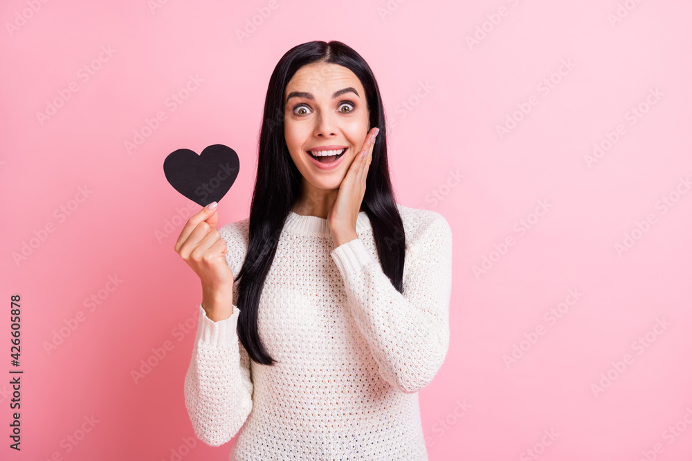 Photo of young attractive happy excited smiling positive girl hold little black heart isolated on pink color background Photo of young attractive happy excited smiling positive girl hold little black heart isolated on pink color background