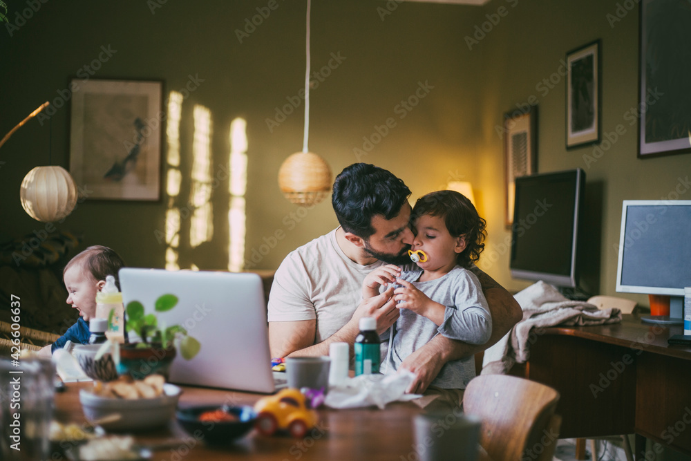 Father kissing son at table in living room Father kissing son at table in living room