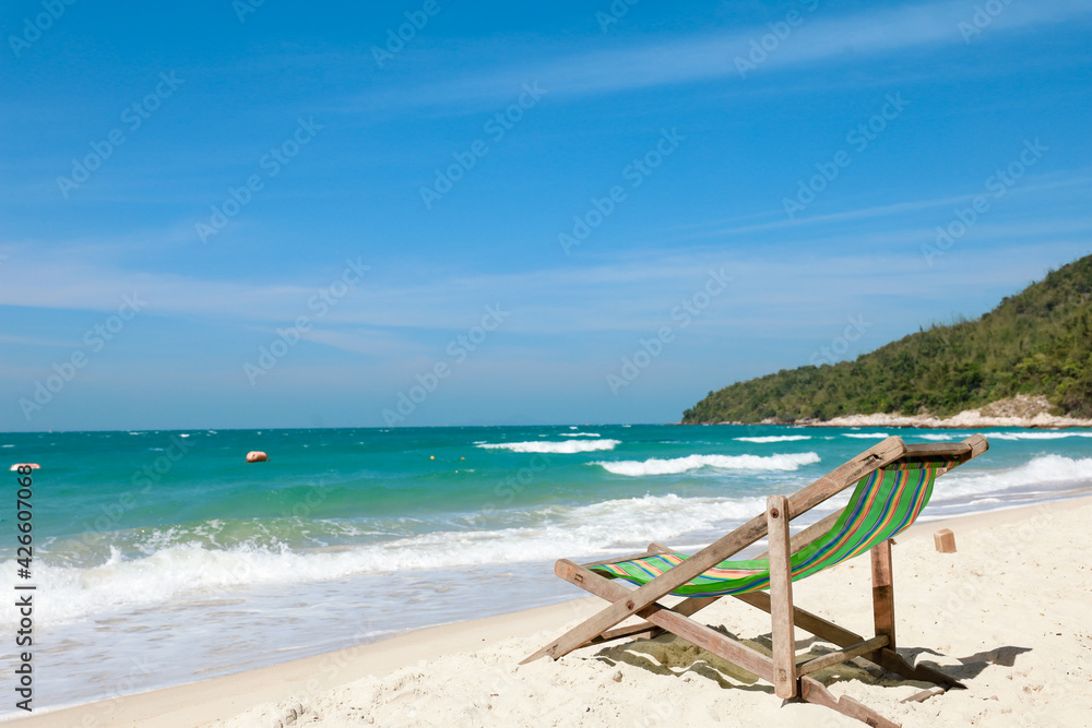 Green Deck chair at the tropical sandy beach with blue wave and clear sky in summer time