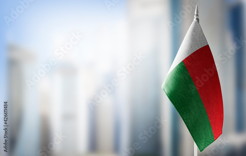 A small flag of Madagascar on the background of a blurred background