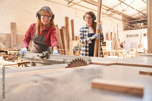 Woman as a craftsman trainee works on the circular saw