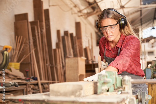Woman as a carpenter trainee planing wood photo