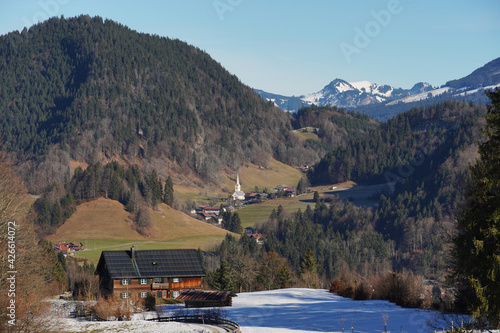 Winteruntypisches Bergpanorama in den Allgäuer Alpen mit grünen Talflanken und Schnee nur auf den Gipfeln